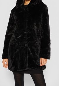 Svart faux fur-kappa med huva, med en mjuk textur, helärmade och rak passform. Framsidan har matchande knäppningar.