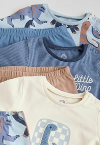 Vier kledingstukken voor kinderen: een lichtblauw shirt met dierenprint, een marineblauw gestreept shirt, een crèmekleurig shirt met de tekst "Little Dino" en een paar bruine broeken.