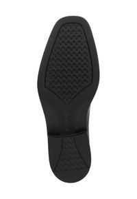 Semelle de chaussure en caoutchouc noir avec une surface texturée présentant un motif chevron et des trous de ventilation. Marquée avec la marque "GEOX".
