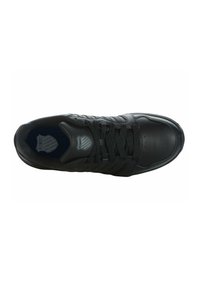 Scarpa sportiva nera con tomaia in pelle liscia, pannelli in nylon testurizzato, punta rotonda e lacci piatti. Presenta un logo sulla soletta.