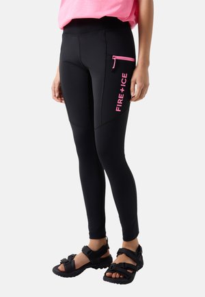 Osoba ubrana w czarne legginsy z różową kieszonką na zamek z napisem "FIRE+ICE" oraz czarne sandały na paski, stojąca na tle jednolitym.