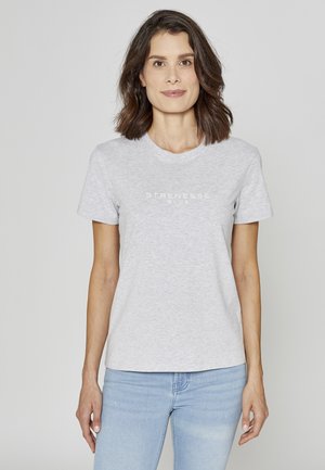 Lys grå kortærmet T-shirt med rund halsudskæring og trykt teksten "STRENESSE BLUE" på tværs af brystet, kombineret med blå jeans.