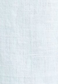 Tissu tissé blanc lâche avec une texture visible en forme de grille et des variations subtiles dans l'épaisseur du fil.
