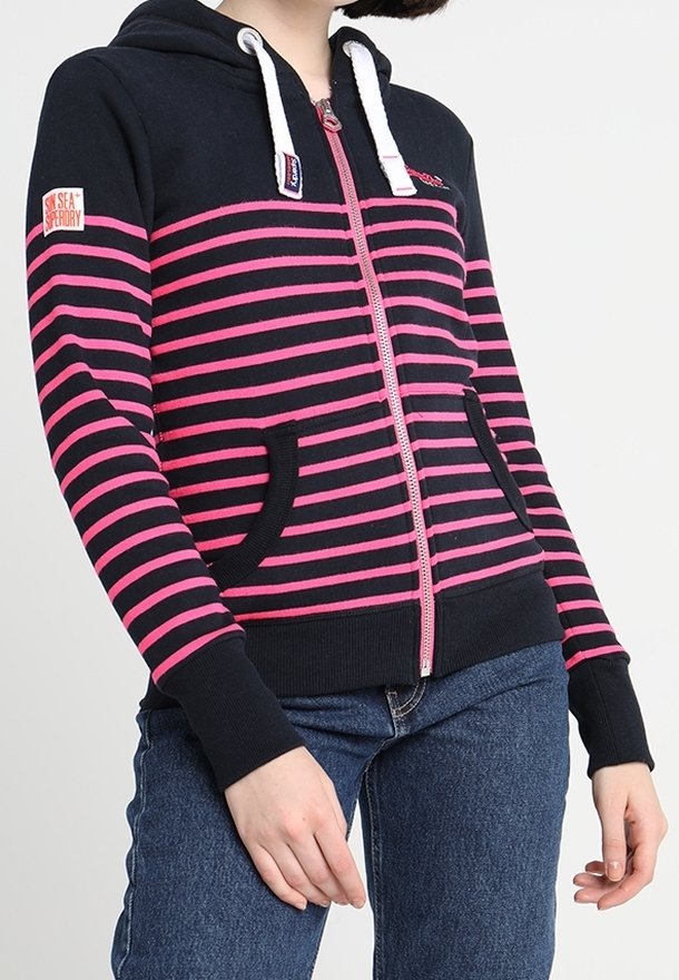 Felpa con zip di colore blu navy, con strisce orizzontali rosa, cappuccio con cordino e due tasche frontali. Presenta polsini e orlo a coste.
