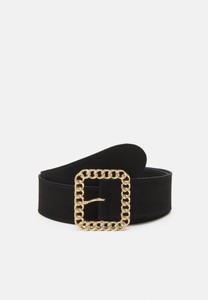Ceinture large noire avec une grande boucle carrée en chaîne dorée, roulée sur un fond blanc.
