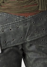 Gröna byxor i konstläder med silverfärgad niteteknik, ett lagerdesign och ett kontrasterande texturerat tyg upptill.