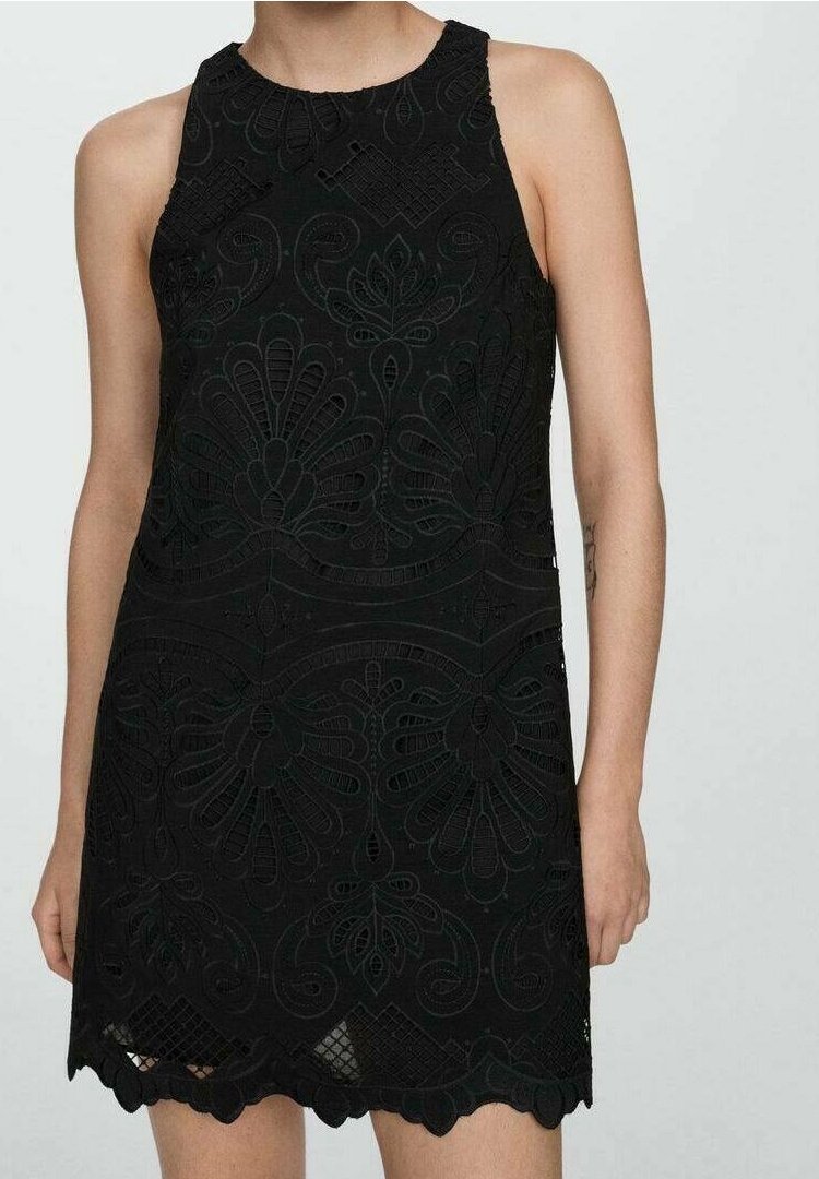 Robe noire sans manches avec des motifs complexes en dentelle florale et un ourlet festonné, portée par une personne aux bras et jambes nus visibles.