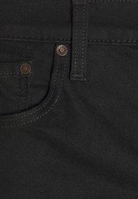 Tissu en denim noir avec poche avant, petite poche pour pièces, passants de ceinture et deux rivets métalliques près des bords de la poche.