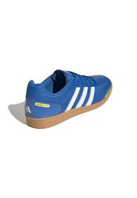 Chaussure de sport bleue en matériau synthétique avec trois rayures blanches, une semelle en caoutchouc, des accents en mesh et une étiquette jaune "SPEZIAL LIGHT".