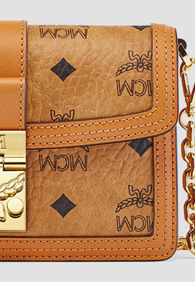 Tan læder designer håndtaske med sorte MCM-logoer, guld lås og kæde-rem detaljer.