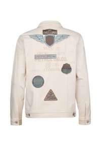 Chaqueta de mezclilla blanca con múltiples parches bordados, incluidos "Daytona 500", varios logotipos y formas geométricas en azul, marrón y gris.