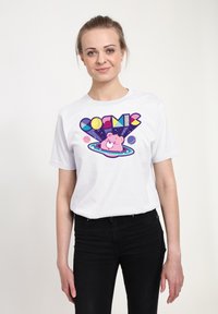 Hvid bomulds T-shirt med en farverig "COSMIC" grafik, der viser en tegneserie bjørn i en galakse, sat mod en mørk rummet baggrund.