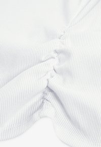 Bela tkanina z rahlo rebrasto teksturo, zložen na enem robu, prikazuje gladek in mehak videz.