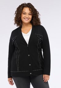 Cardigan negru cu decolteu în V, decorat cu strasuri metalice pe partea din față și buzunare. Material moale cu închidere cu nasturi.