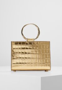 Borsa in ecopelle dorata con texture coccodrillo, forma rettangolare e manico metallico circolare. Superficie liscia e lucida senza ulteriori rifiniture.