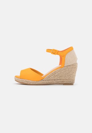 Sandale compensée jaune avec bride à la cheville, bout ouvert, talon tissé et semelle en corde texturée.