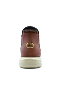 Bottines en faux cuir marron avec un col en tissu noir texturé, présentant un emblème circulaire à l'arrière et une semelle en caoutchouc blanc.