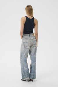 Dżinsy z wysokim stanem, w kolorze wyblakłego niebieskiego, o luźnym kroju, z 5 kieszeniami i przetarciami. Do tego granatowy top na ramiączkach.