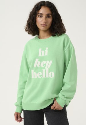 Minzgrüner Crewneck-Pullover aus weichem Stoff, mit oversized Passform und weißem Text "hi hey hello" auf der Vorderseite.