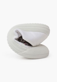 Sneaker bianca in tela con una forma arrotondata, suola flessibile e rivestimento interno a fantasia floreale. Cuciture visibili sulla tomaia e sulla suola.