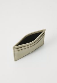 Portafoglio in pelle beige con diversi scomparti per carte, texture liscia e design minimalista. Presenta una cucitura discreta e un piccolo logo in rilievo.