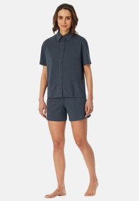 Marinblå kortärmad skjorta med knappstängning och ögla spetsdetalj i botten, ihop med matchande shorts. Mjuk, lättviktig tyg.