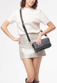 Sort læder crossbody taske med guldhardware, rektangulær form, glat tekstur, justerbar strop og minimalistisk design.