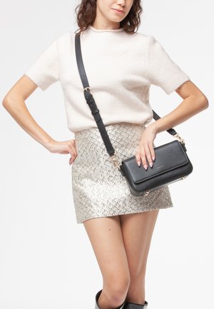 Borsa a tracolla in pelle nera con finiture dorate, forma rettangolare, texture liscia, tracolla regolabile e design minimalista.