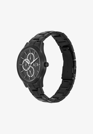 Melna rokas pulksteņa ar sudraba akcentiem, apaļa seja, trīs subdiali un metāla saitīšu aproce. Minimālistisks dizains ar teksturētu virsmu.