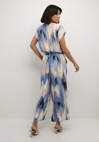 Giubbino blu e beige con motivo, maniche corte, vita con fiocco, pantaloni larghi e una texture di tessuto morbido. Spalline sottili e vestibilità comoda.