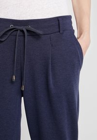 Marina joggerbyxor gjorda av mjukt tyg, med dragsko i midjan, framfickor och en avslappnad passform. Texturerad yta med subtil variation.