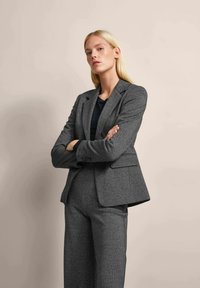 Gray textured blazer with notched lapels, two front pockets, and a tailored fit, paired with matching pants. Solid black top underneath.