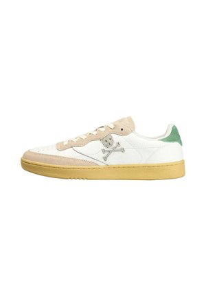 Zapatilla blanca de caña baja con detalles en ante beige, lengüeta verde en el talón, suela amarilla y logo bordado de calavera y huesos cruzados en el lateral.