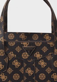 Pattern di logo marrone su una borsa in sintetico nero testurizzato con manici doppi e un evidente tag in metallo a forma di triangolo.