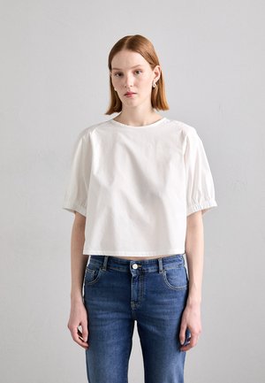 Top in cotone bianco a maniche corte con scollo rotondo e maniche arricciate, abbinato a jeans in denim blu con stile classico delle tasche.