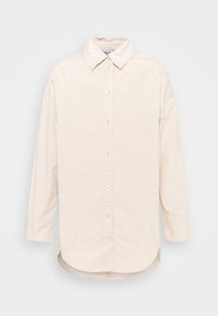Camicia beige a maniche lunghe con colletto appuntito, orlo dritto e bottoni bianchi, realizzata in tessuto morbido con una superficie liscia.