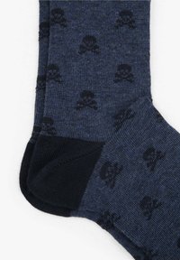 Calcetines azul oscuro con un patrón de calaveras y huesos cruzados en negro, con secciones de puntas y talones en negro sólido, sobre un fondo blanco.