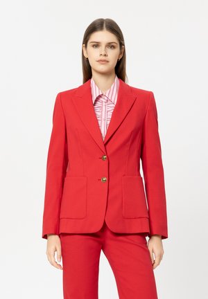 Roter Blazer mit strukturiertem Design, zwei Vorder pockets, goldene Knöpfe, kombiniert mit einem hellrosa-weiß gestreiften Hemd.