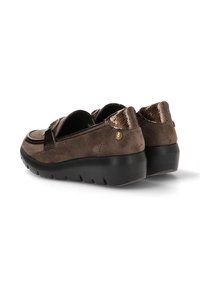 Zapatos de ante marrón con un acento de charol brillante en el talón, que presentan una suela negra gruesa y baja, además de un detalle decorativo en forma de correa.