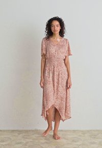 Vestido maxi de patrón rosa con mangas cortas, cintura ceñida y dobladillo asimétrico, hecho de tejido ligero y fluido.