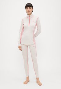 Αθλητικό τοπ με μακριά μανίκια και ψηλό γιακά, καθώς και εφαρμοστά κολάν σε ανοιχτό ροζ χρώμα με πιο σκούρα ροζ ραφές αντίθεσης. Λείο, ελαφρύ ύφασμα.