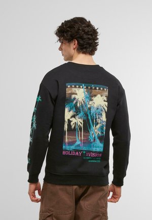 Schwarzer Hoodie mit einem lebendigen Rückenmotiv, das Palmen, Filmstreifenakzente und den Text "HOLIDAY DIVISION" in Lila zeigt.