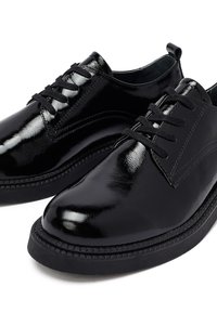 Zwarte gepatenteerde leren schoenen met een gladde afwerking, voorzien van een klassiek vetersluiting ontwerp en een contrasterende rubberen zool. Geaccentueerd met naaddetails.