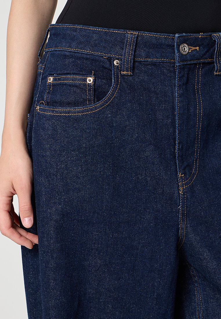 Jeans in denim blu scuro con un classico design a cinque tasche, cuciture arancioni a contrasto e chiusura con bottone in vita.