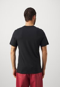 Musta puuvillainen t-paita, jossa on klassinen pyöreä pääntie ja lyhyet hihat. Yksinkertainen muotoilu ja rento istuvuus. Ei merkittäviä kuvioita.