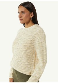 Cremfarbener Strickpullover mit strukturiertem Muster, gerippten Bündchen und rundem Ausschnitt. Besitzt ein dezentes Logo-Detail am Saum.