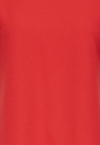 Camiseta roja de manga corta hecha de tela suave, con un color sólido sin patrones ni adornos, mostrando un diseño simple.