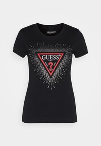 Camiseta de algodón negra con cuello redondeado. Presenta un logo triangular rojo con texto blanco y strass plateados formando un patrón radiante.