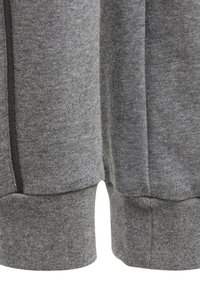 Grå sweatshirtstof med en blød tekstur, der har en lynlås på den ene side og ribbede manchetter i bunden for et tætsiddende look.