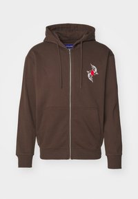 Felpa con zip intera di colore marrone, con tasche frontali, cappuccio regolabile con cordino e una piccola grafica sul petto di due pesci koi bianchi attorno a un cerchio rosso.